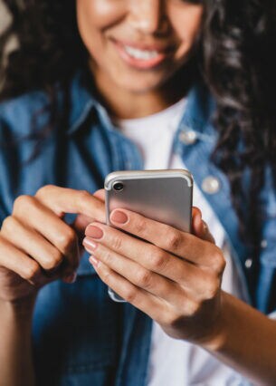 Eine Person tippt auf dem Smartphone, das sie in der Hand hält.