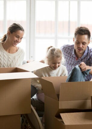 Ein Mann und eine Frau packen mit zwei Kindern Umzugskartons ein oder aus.