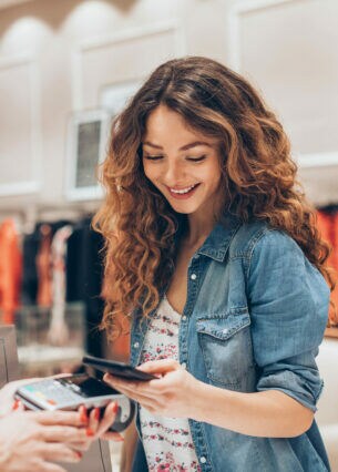 Eine Person bezahlt mit ihrem Smartphone in einem Bekleidungsgeschäft.