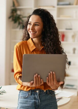 Eine Person lehnt an einem runden Tisch und hält ein geöffnetes Notebook in den Händen.