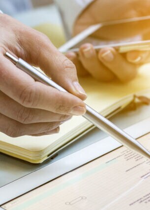 Nahaufnahme von zwei Händen, die mit Smartphone und Tablet arbeiten.