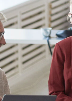 Jüngere und ältere Mitarbeitende eines Unternehmens halten gut gelaunt ein Meeting ab.