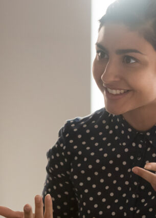 Zwei Mitarbeiterinnen mit verschiedenen kulturellen Hintergründen sitzen an einem Schreibtisch und führen ein Gespräch.