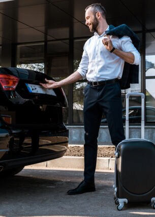 Bild: Perosn mit Koffer öffnet Kofferraum