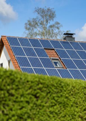 Ein Einfamilienhaus mit Solarpaneelen auf dem Hausdach steht hinter einer grünen Hecke. Nach Berechnungen des Energieversorgers Eon waren in der ersten Hälfte 2023 die Bedingungen zur Solarstromproduktion nirgends in Deutschland so gut wie in Mecklenburg-Vorpommern. Doch im Ländervergleich hinkt der Nordosten bei der Sonnennutzung hinterher. (zu dpa: «Eigenheimbesitzer planen häufig mit Sonnenstrom»)