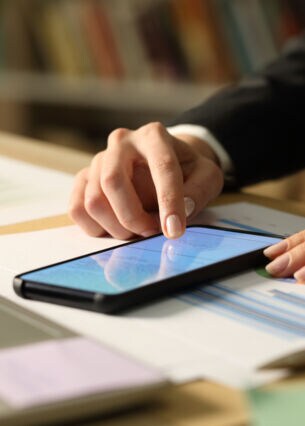 Artikelbild Person klickt am Smartphone am Schreibtisch