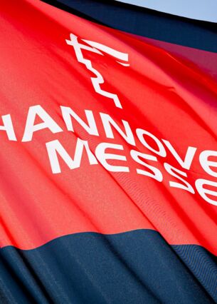 Eine Fahne zur Hannover Messe weht im Licht der Sonne auf dem Messegelände. Microsoft präsentiert auf der Hannover Messe neuartige virtuelle Assistenten mit Künstlicher Intelligenz für den breiten Einsatz in der Industrie. (zu dpa: «Microsoft stellt KI-Assistenten für Industrie-Einsatz vor»)