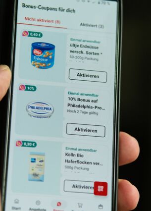 Auf dem Bildschirm eines Smartphones ist die Rewe-App mit dem Bonus-Bereich geöffnet. (zu dpa: «Kunden vermissen gedruckte Werbeprospekte»)