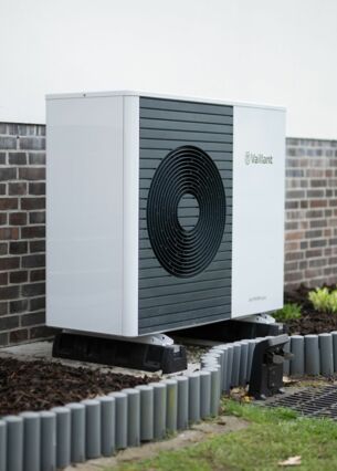 Wärmepumpe vor einem Einfamilienhaus (zu dpa: «Wärmepumpen setzen sich bei Neubauten durch»)