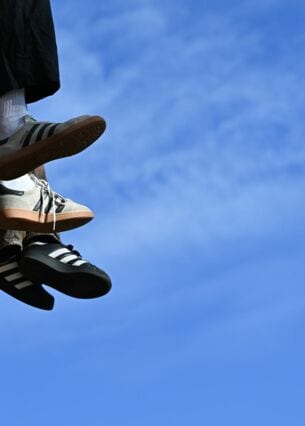 Ein junges Pärchen sitzt bei mildem, sonnigen Herbstwetter und blauem Himmel auf einer Mauer am Mainkai und lässt die Beine baumeln. (zu dpa: «Sneaker hoch im Kurs - Kein Ende des Booms in Sicht»)