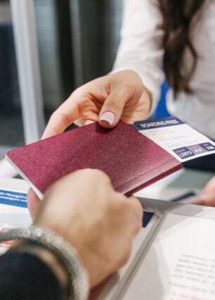 Person übergibt Fluggast ihren Reisepass wieder am Flughafenschalter