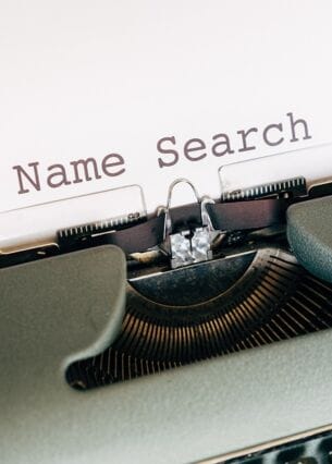 Nahaufnahme einer klassischen Schreibmaschine mit einem Blatt Papier, auf dem der Text ‚Name Search‘ steht. Das Bild symbolisiert die Suche nach einem Namen, etwa für ein Unternehmen, Produkt oder Projekt