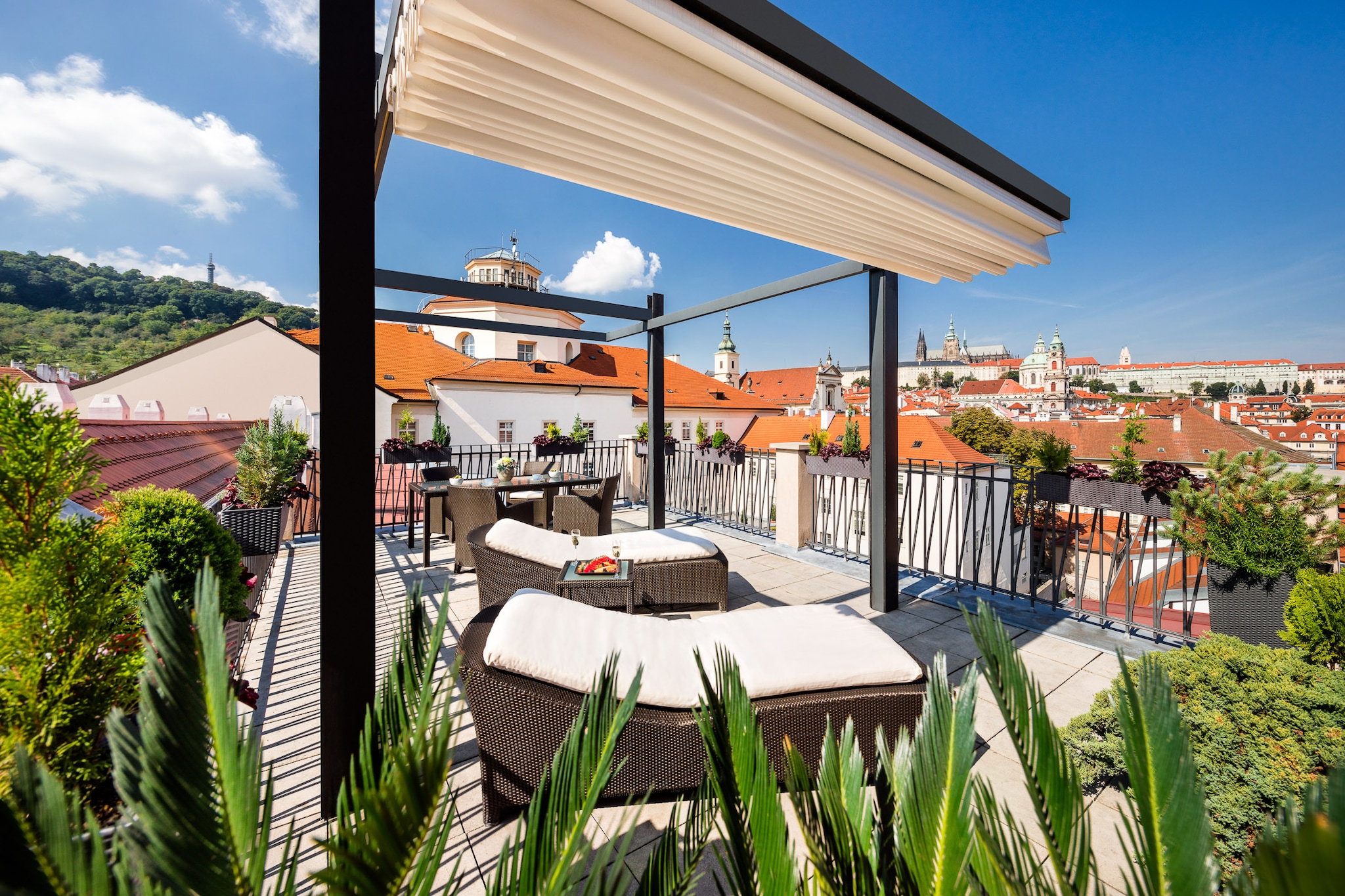 The terrace of the Presidential Suite is ringed with potted plants. A retractable awning is set up over two sun beds looking over the city.