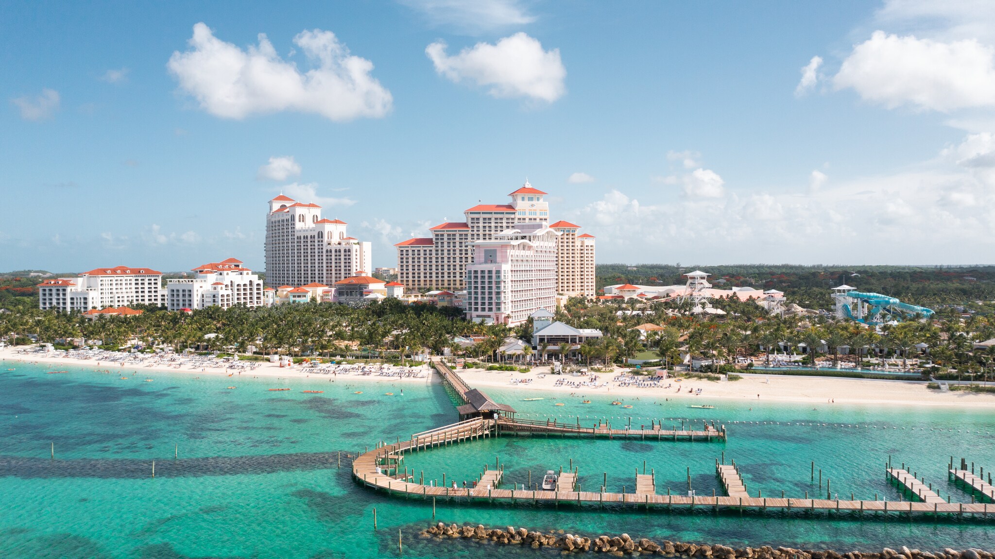 Beyond the blue-green water of the sea, extensive docks, and white-sand beaches, the resort rises as an imposing series of buildings.