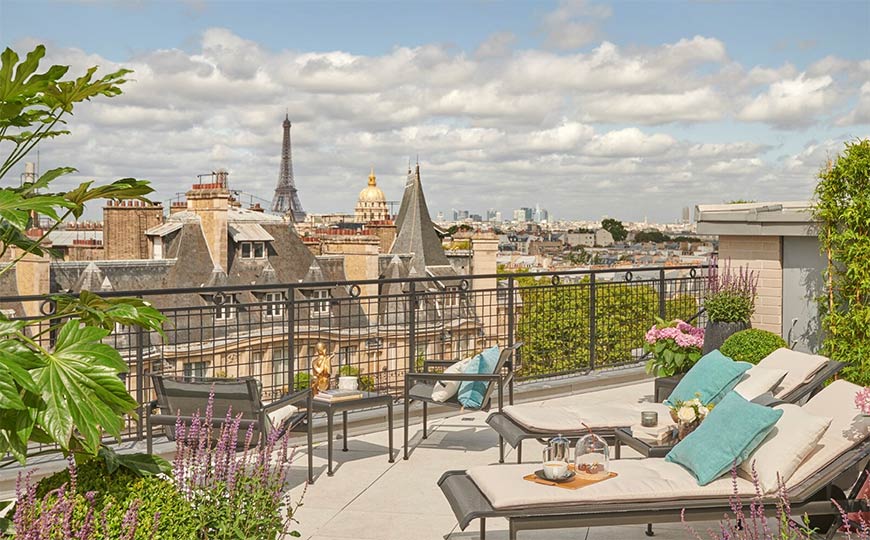 A group of travelers rides a small, covered boat over blue-green water towards inviting, lushly-jungled mountains.