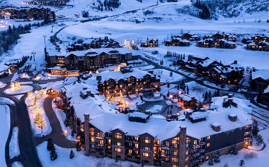 A group of travelers rides a small, covered boat over blue-green water towards inviting, lushly-jungled mountains.