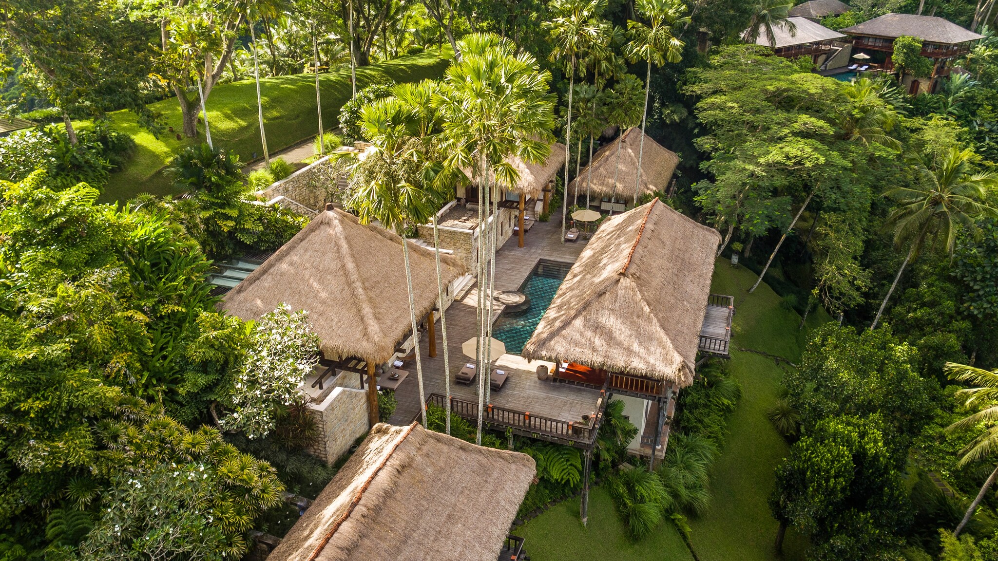 Aerial view of the Tejasuara Residence, which is composed of several thatch-roofed hutches surrounding a central deck with a private pool.
