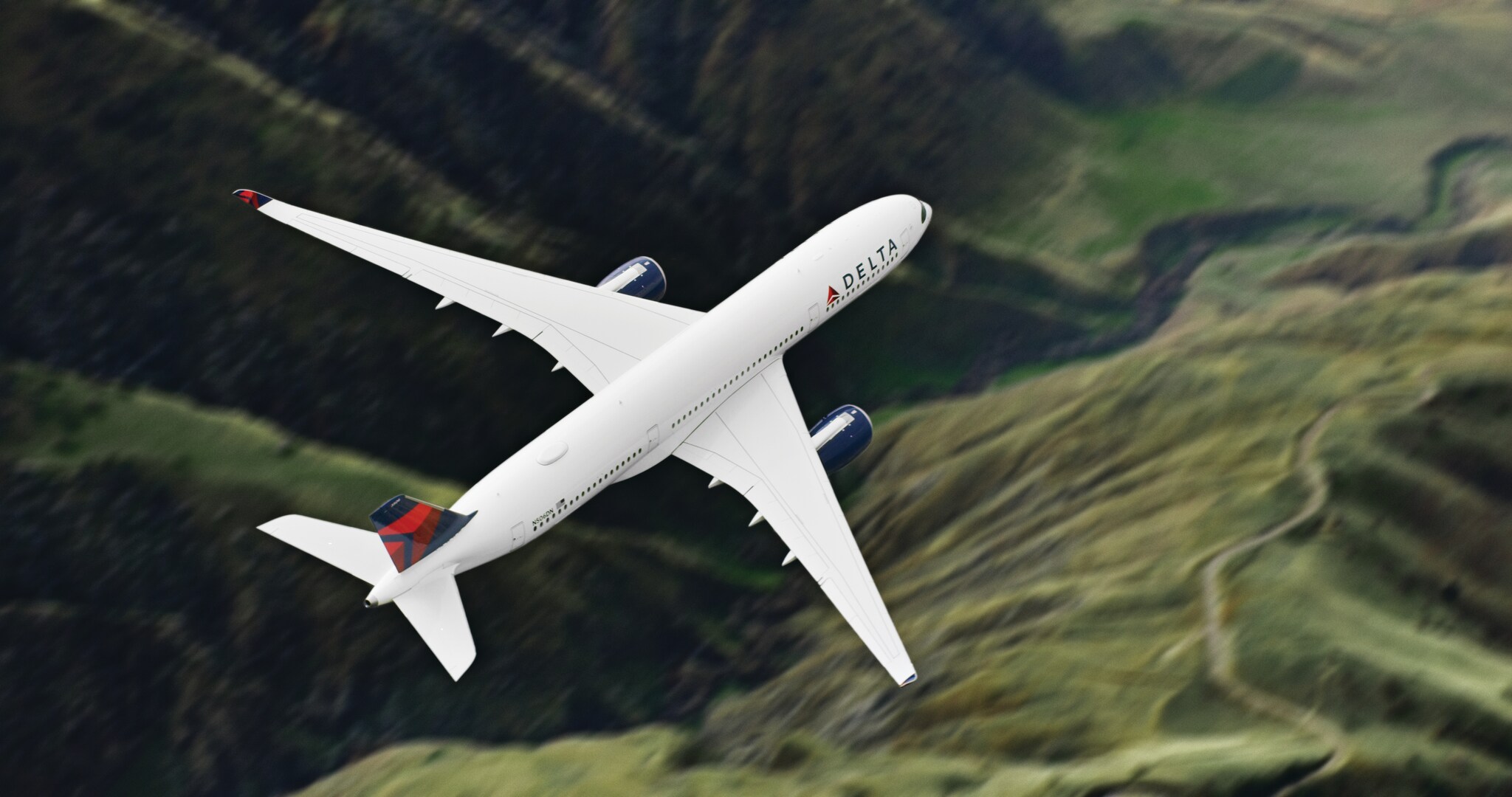 A Delta plane flies over a grassy valley.