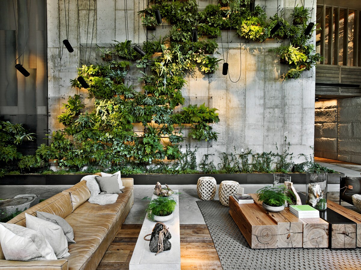 The hotel lobby is high-ceilinged and semi-industrial, softened by light, casual furniture and lattices of plants covering the walls.