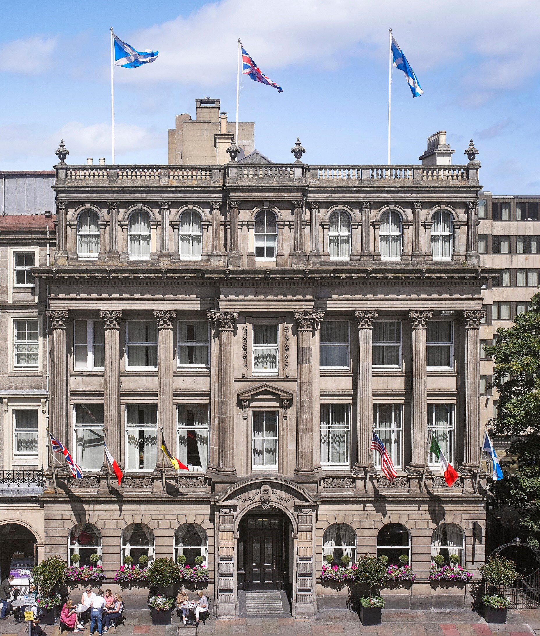 The main entrance of InterContinental Edinburgh The George is built of gray stone, dominated by columns and a row of flags.