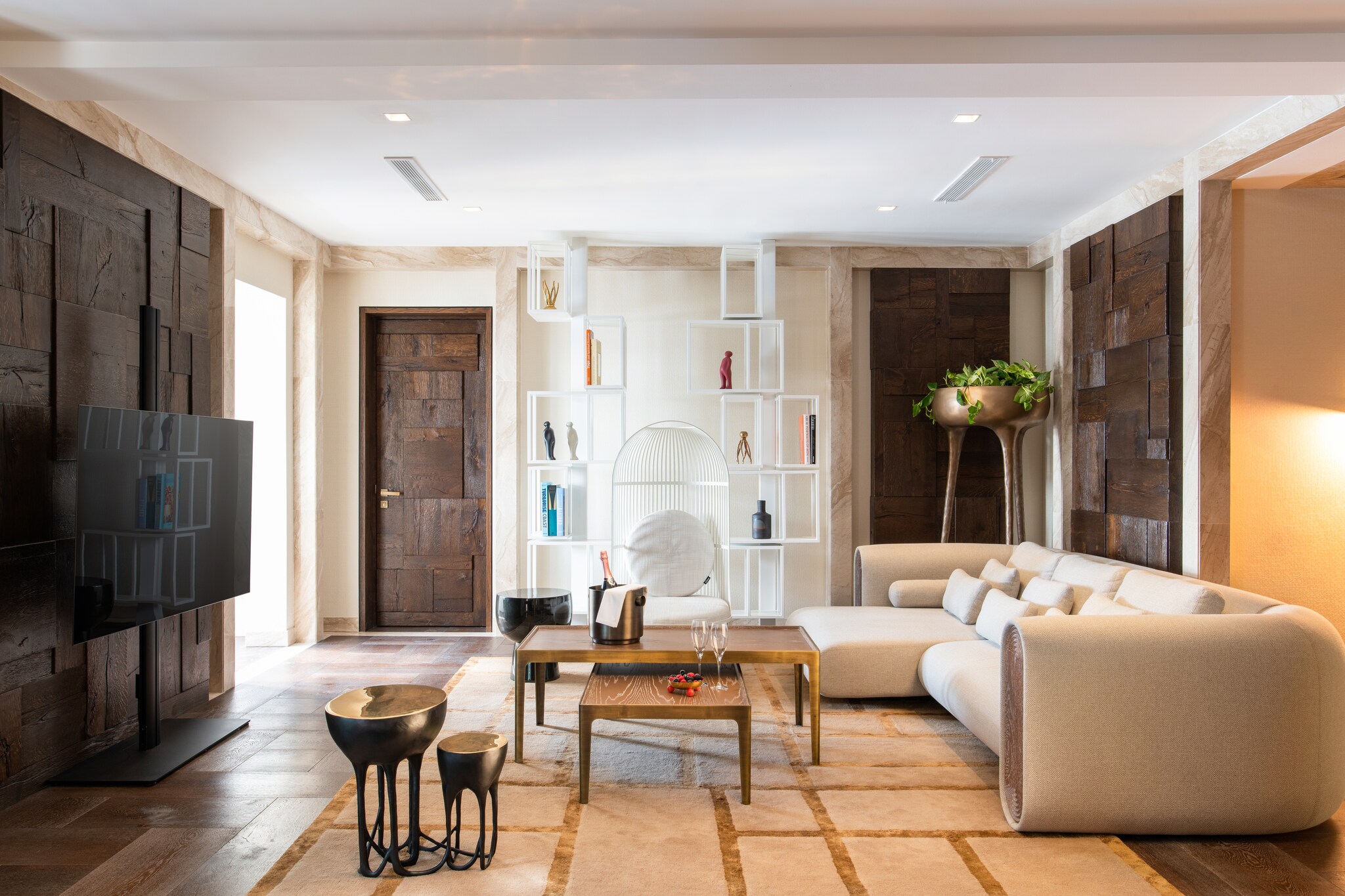 The Grand Residence Living Space features a large, curved white couch, a birdcage-like white chair, and bookcases with offset white boxes.