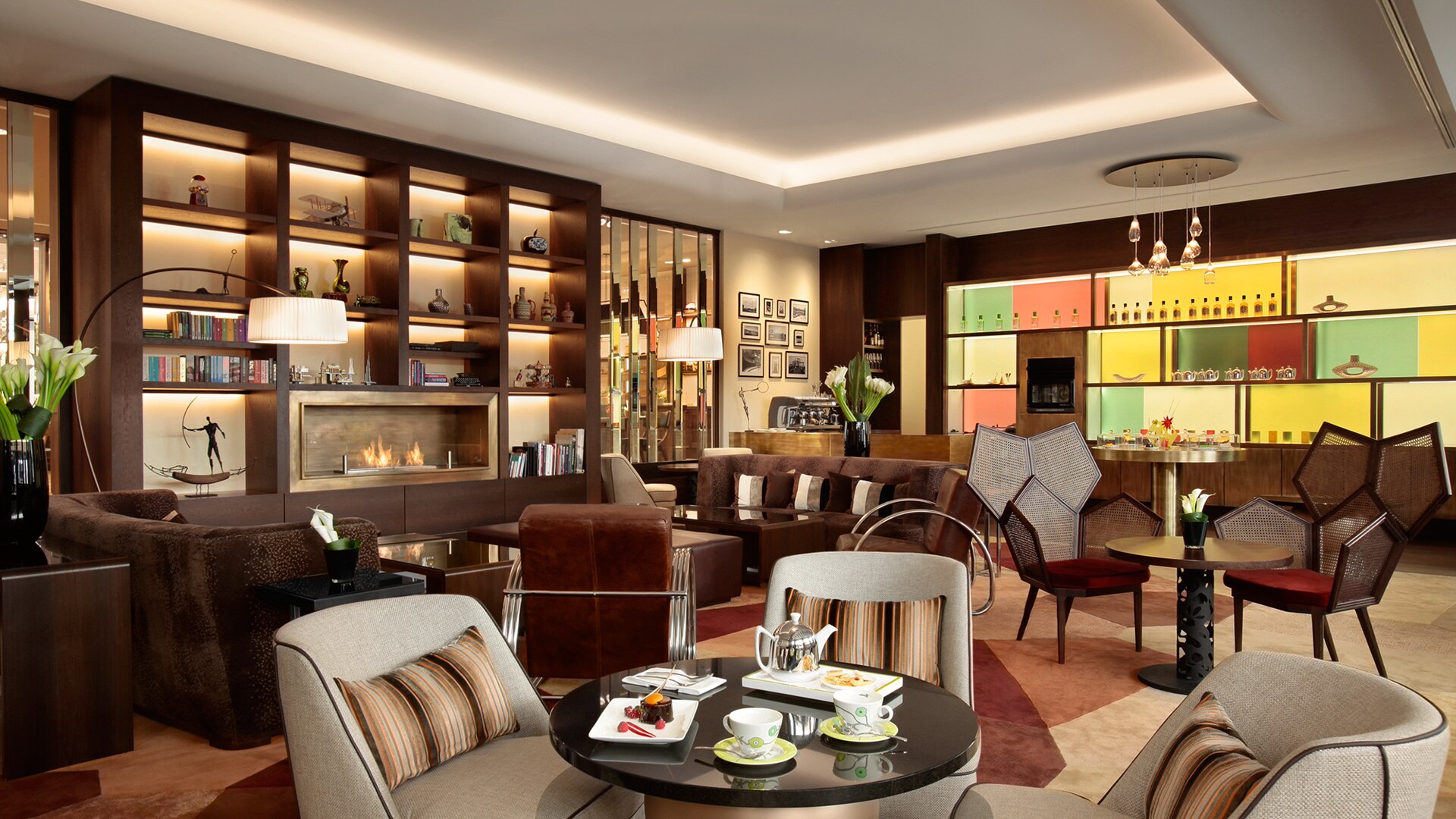 The Living Room, the hotel’s coffee house, features seats in grays and browns surrounded by backlit shelves full of books and curios.