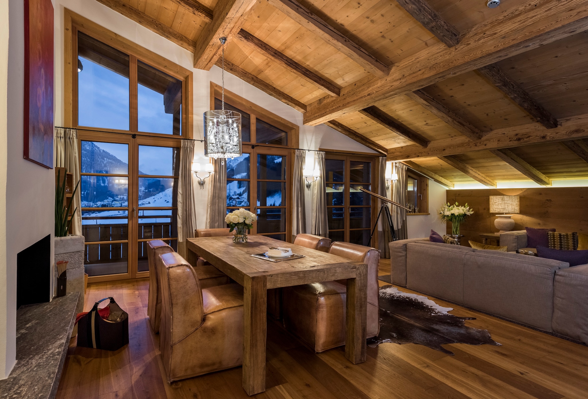 The living room of the master suite has a slanted wooden ceiling and a large wooden table seated with leather chairs.