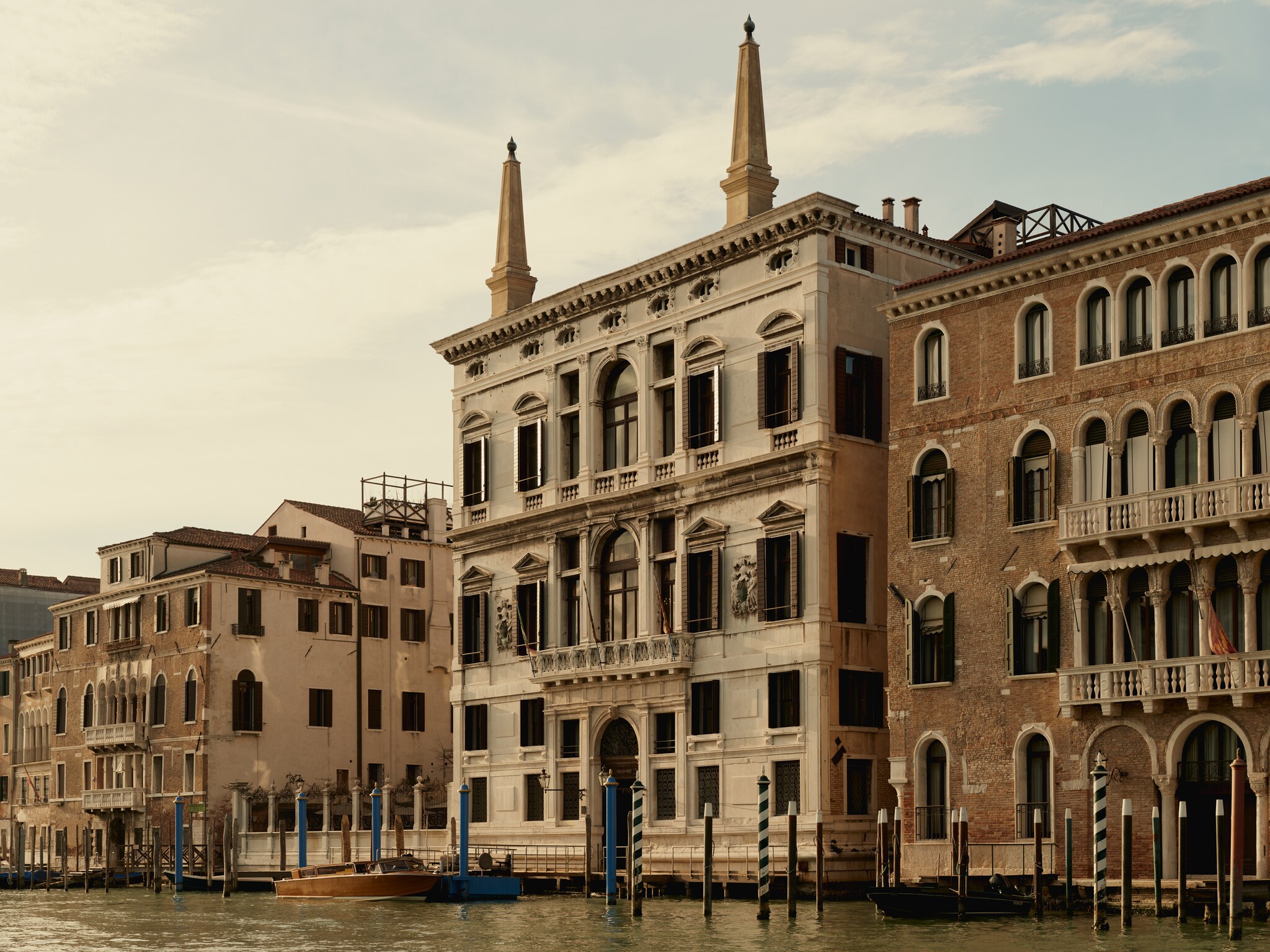 Exterior of the Aman Venice, a white building with a stately façade, including columns around the doors and pediments above the windows.