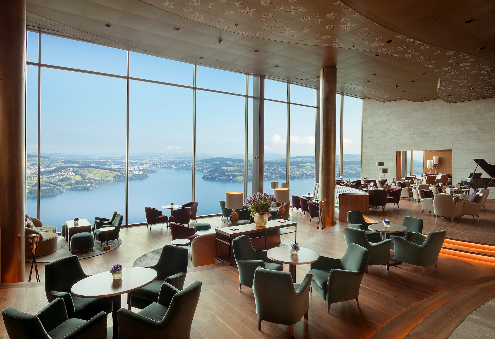The Lakeview Bar & Cigar Lounge is lit by floor-to-ceiling windows overlooking Lake Lucerne. Oblong tables are surrounded by plush armchairs.