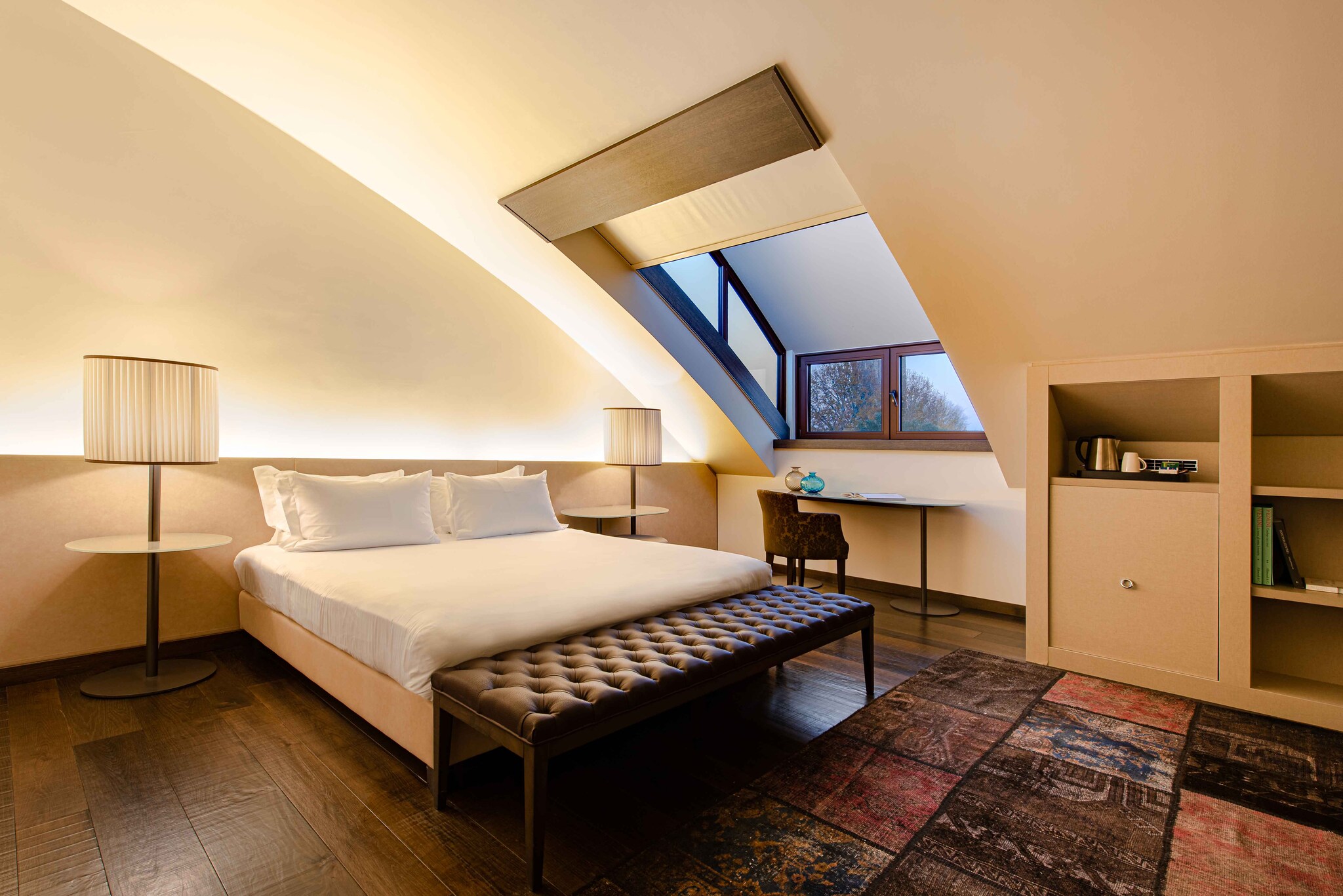 In a bedroom at the Hyatt Centric Murano Venice, the roof curves over the bed and a small desk set under a window.
