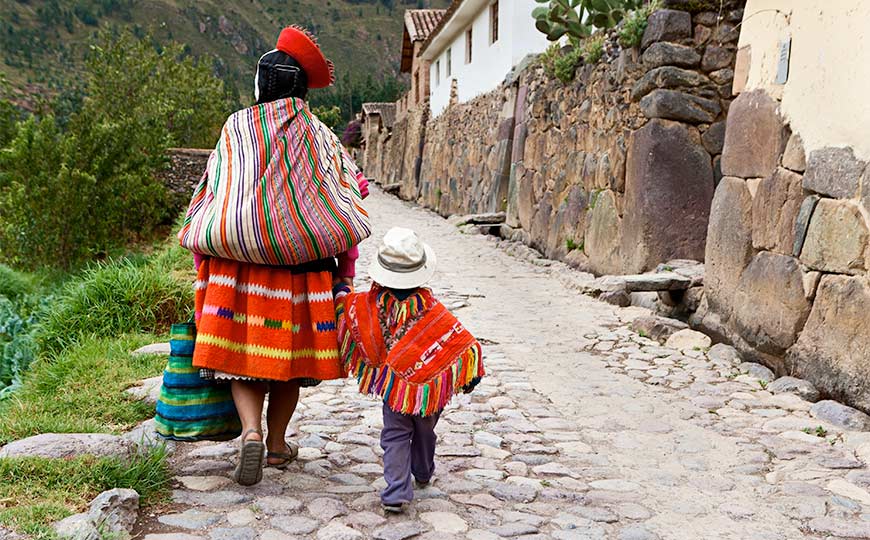 Mother and daugther in Pery colorfully dressed walking down a cobblestone street.