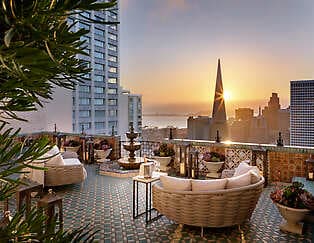 Terrace of suite at Fairmont San Francisco with view of San Francisco skyline and bay at sunset.