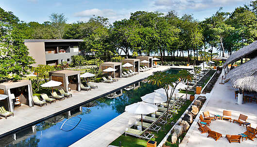 Hotel pool & privates cabanas in front of the beach, surrounded by nature.