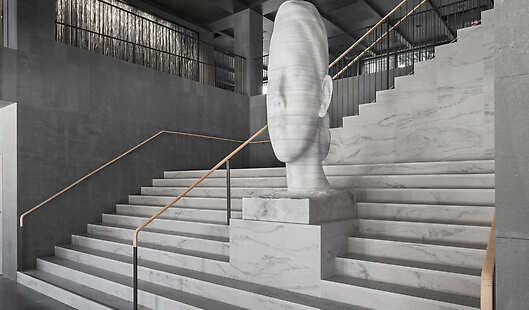 The grand staircase of At Six with the signature piece by Jaume Plensa