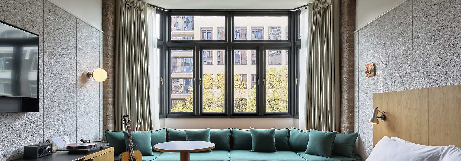 A spacious room at Ace Hotel Sydney, with a king bed, a daybed, extra high ceilings, original brickwork, bathtub and walk in shower. 