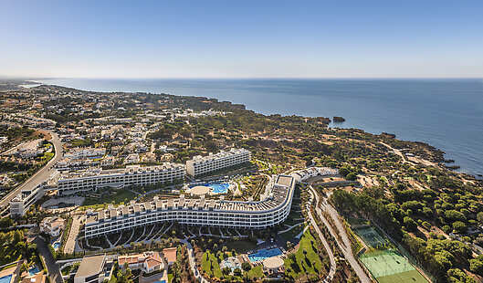 Modern coastal resort with swimming pools, landscaped gardens, and sports facilities. It sits on the coastline overlooking the ocean.