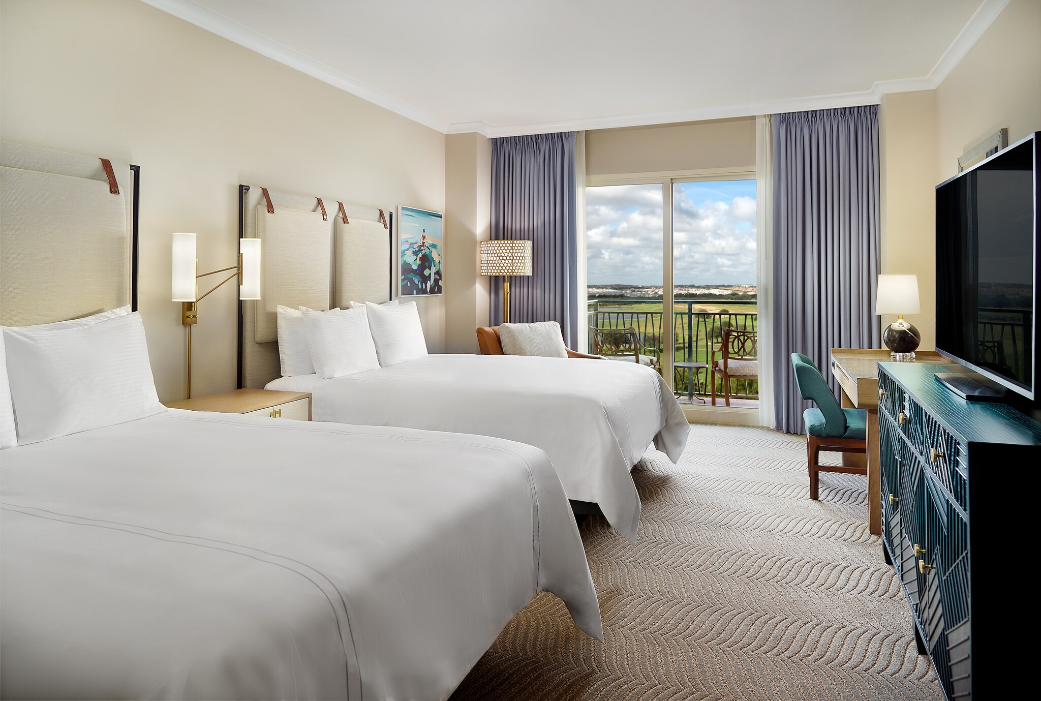 In a Premiere Room at the Omni Orlando Resort at Championsgate, the carpet is gray and wave-textured, and blue curtains frame balcony doors.