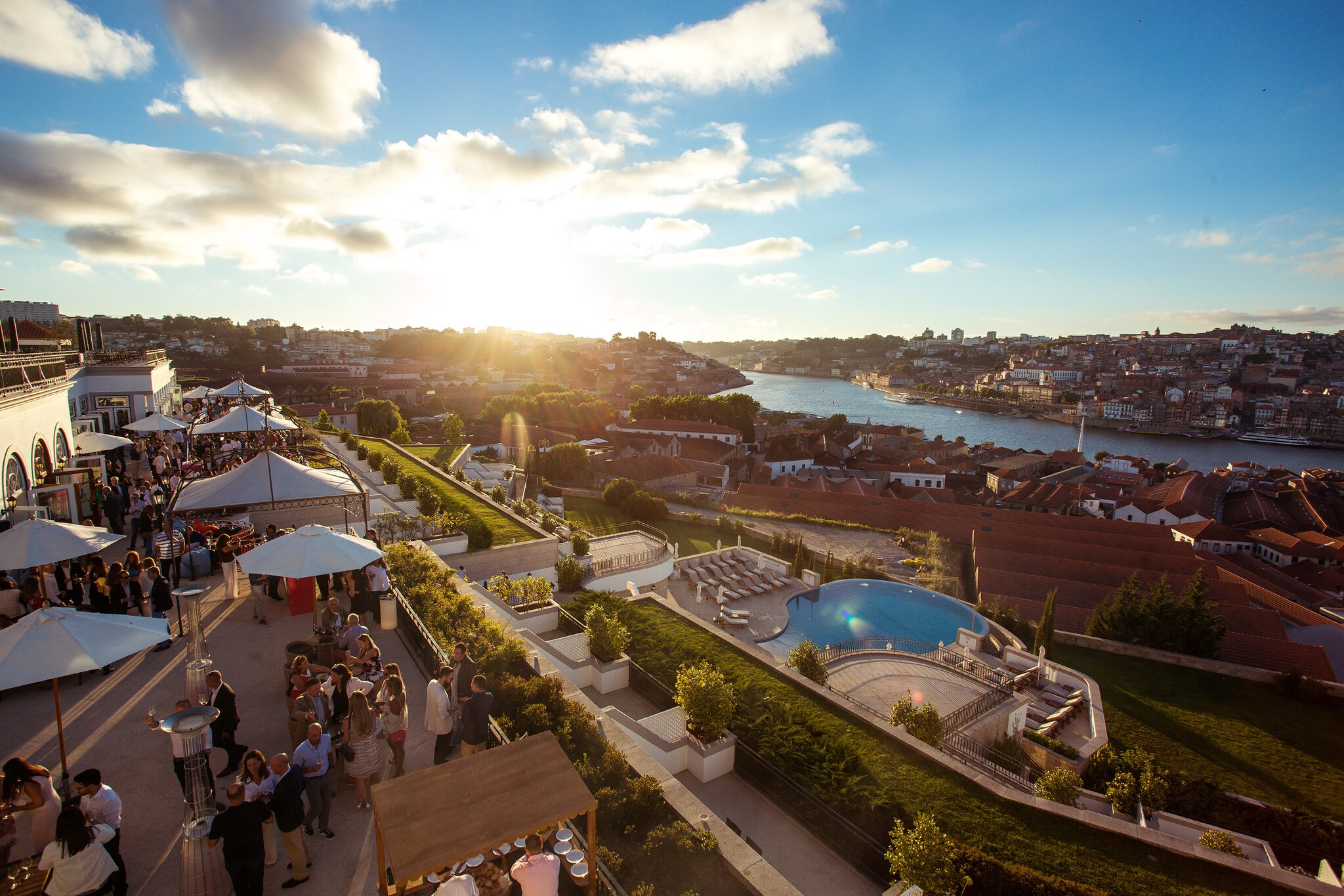 Aerial view of the hotel’s Sunset Wine Party. Guests throng the terrace around umbrellas, tends, and freestanding heaters.
