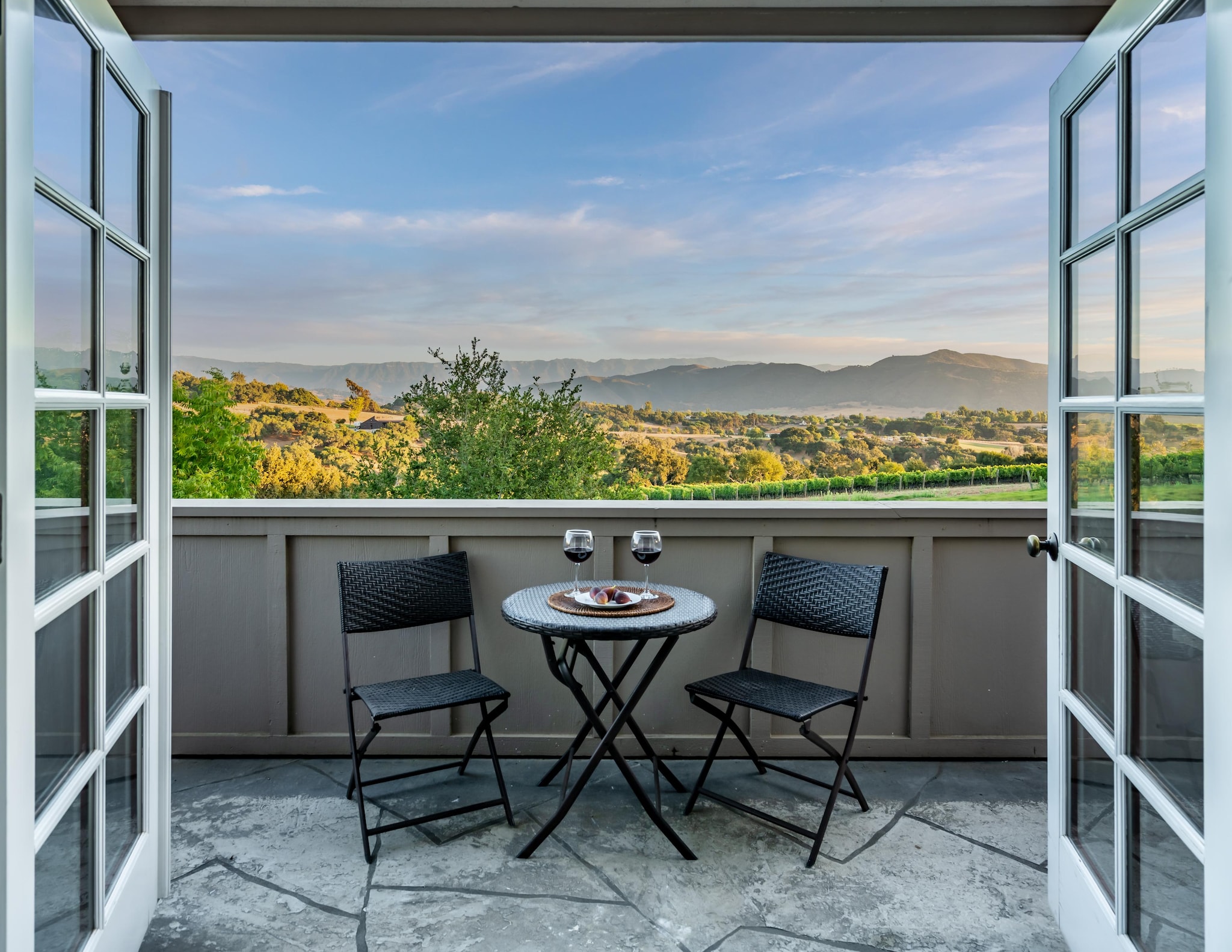 Bistro table seating on outdoor terrace with view of surrounding countryside and mountains.