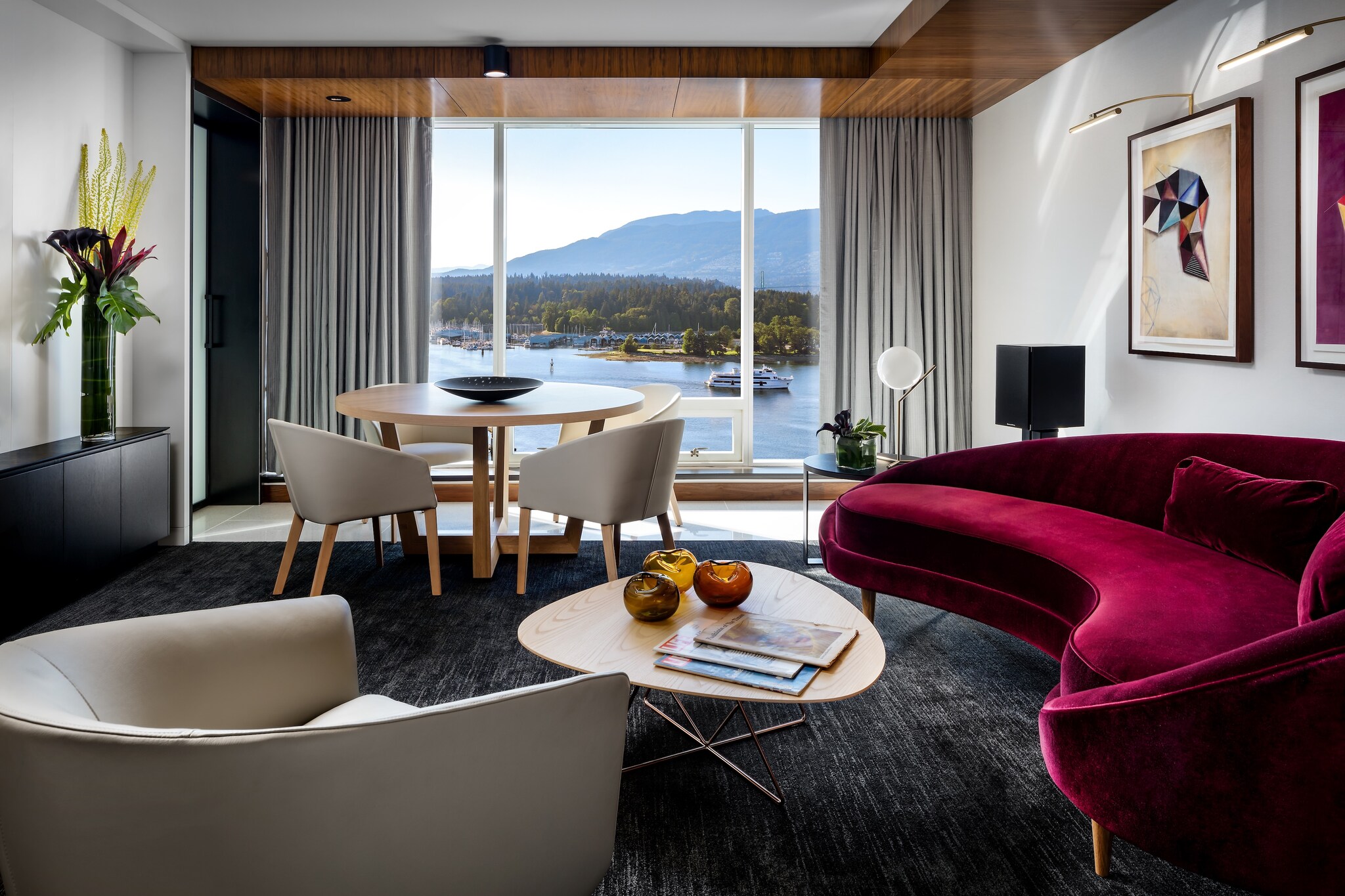 The living room of the Fairmont Gold Owners’ Suite features a raspberry-red velvet couch and floor-to-ceiling windows overlooking the water.