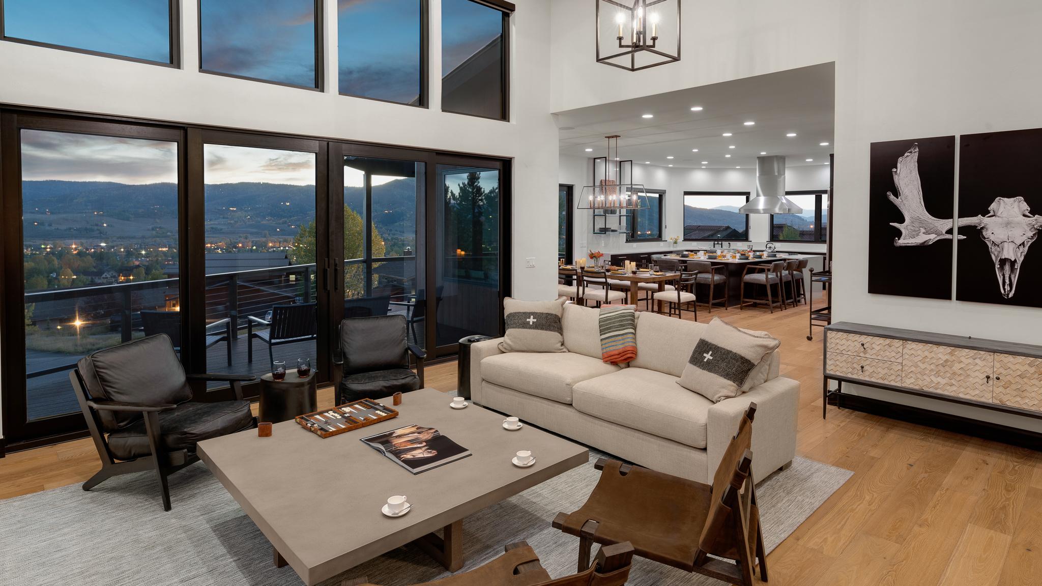 Interior of modern living and dining areas with views of mountains through expansive windows.
