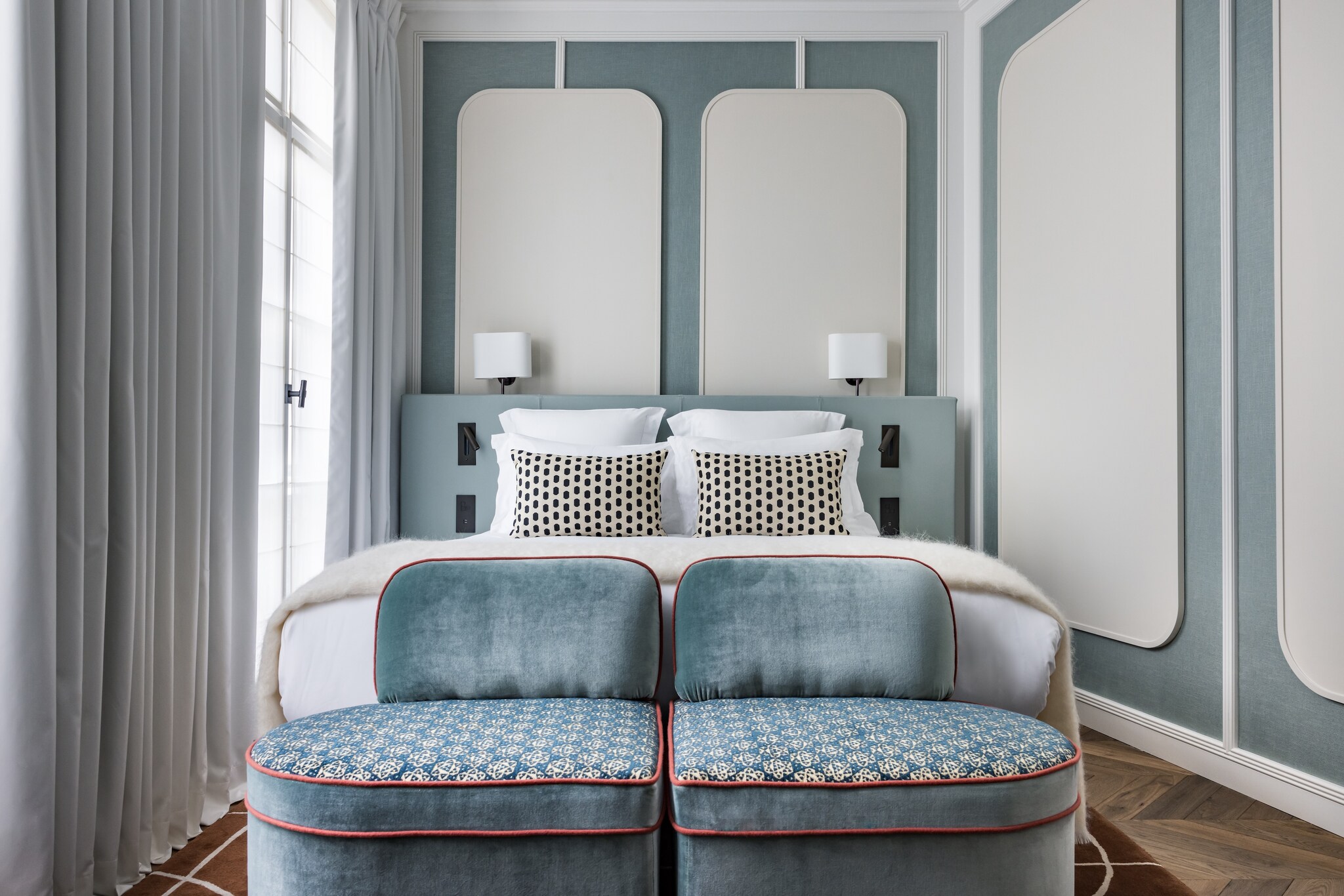 In a deluxe room in Le Pavillion Faubourg Saint-Germain, velvet powder-blue chairs at the foot of a bed match the walls and headboard.