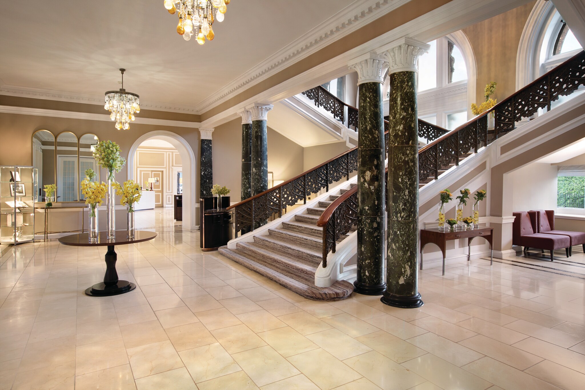 The hotel lobby, which is mostly white marble, features burgundy furniture and a sweeping staircase flanked by black marble columns.