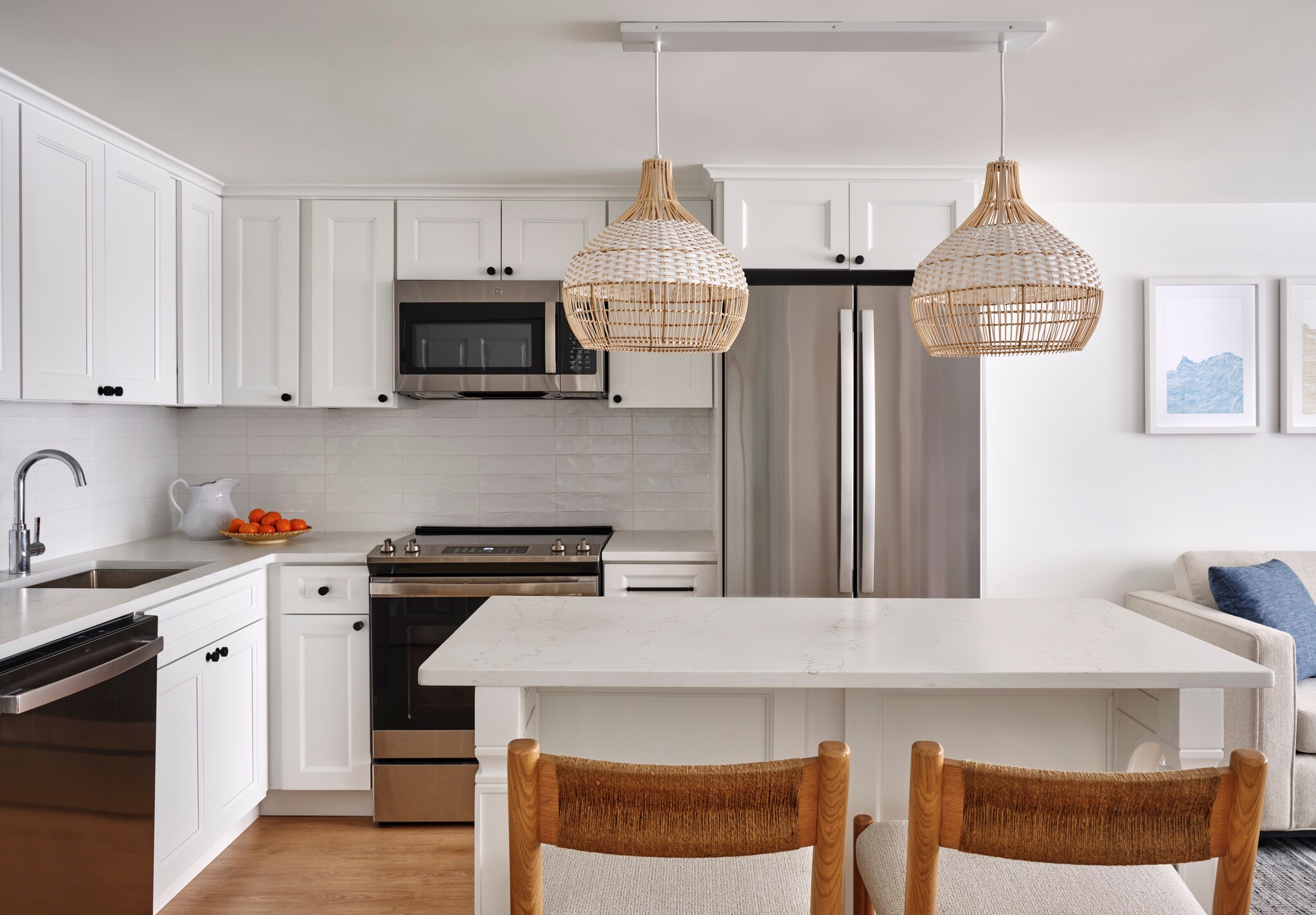 In the kitchen of a cottage/townhouse at the Red Jacket Beach Resort & Spa, the cabinets and counters are all white under basket chandeliers.