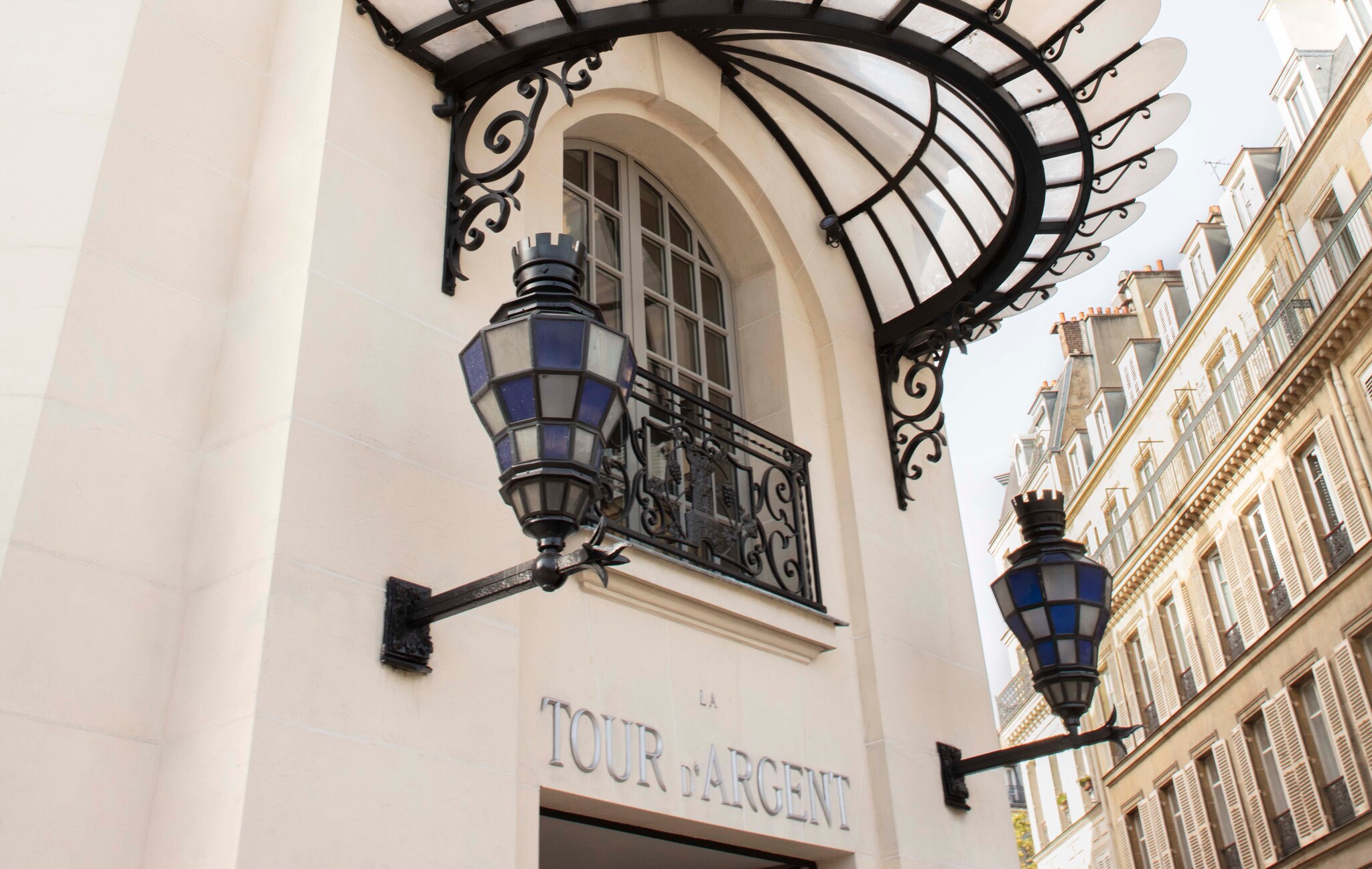 The name Tour D’Argent is written in silver above the door. Two stained-glass lamps are fixed on either side, with a small glass awning above.