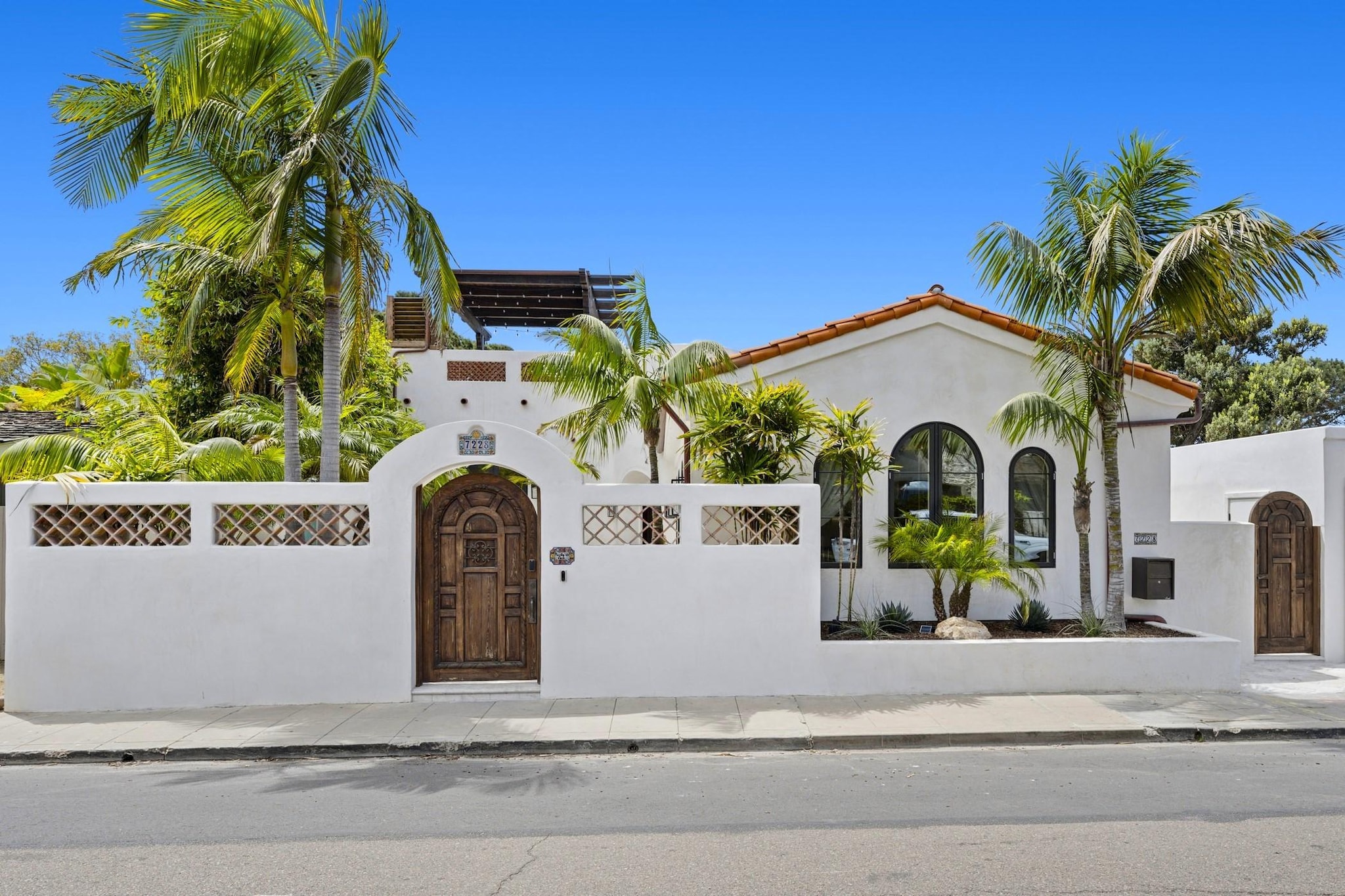 Exterior of Spanish style white stucco house highlighting rustic wood door leading to interior courtyard