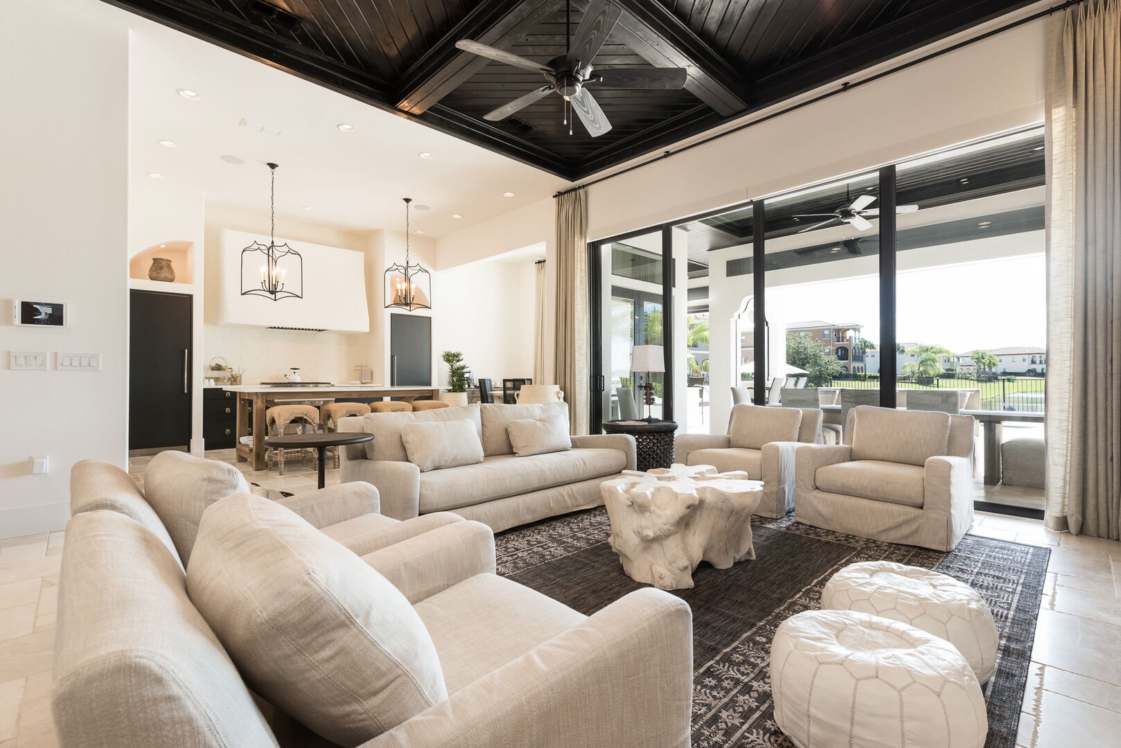 Bright modern interior of kitchen, dining, and living area with expansive windows.