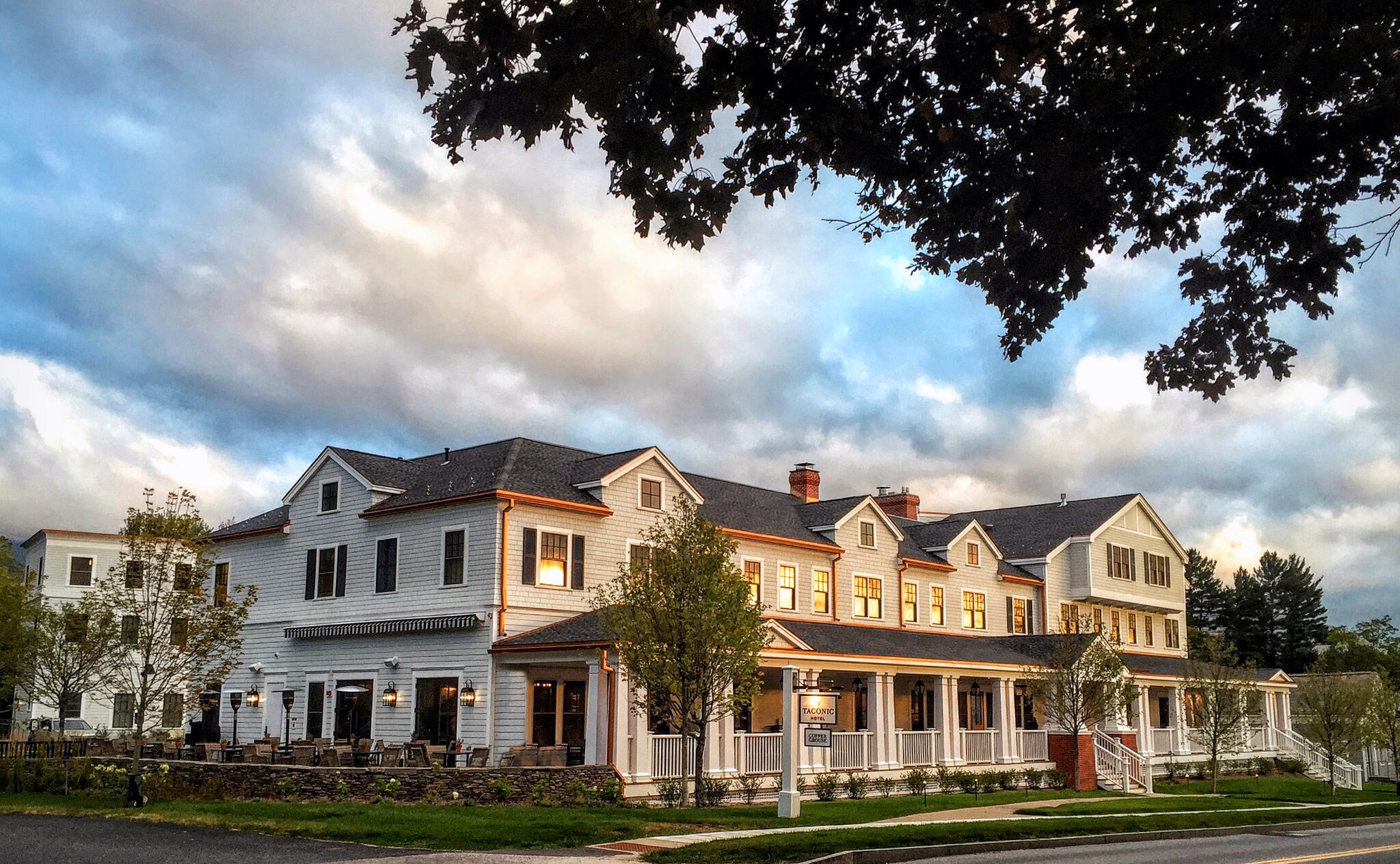 Exterior view of the hotel, a long two-story building in a residential clapboard style. The windows on the upper floor reflect sunset.