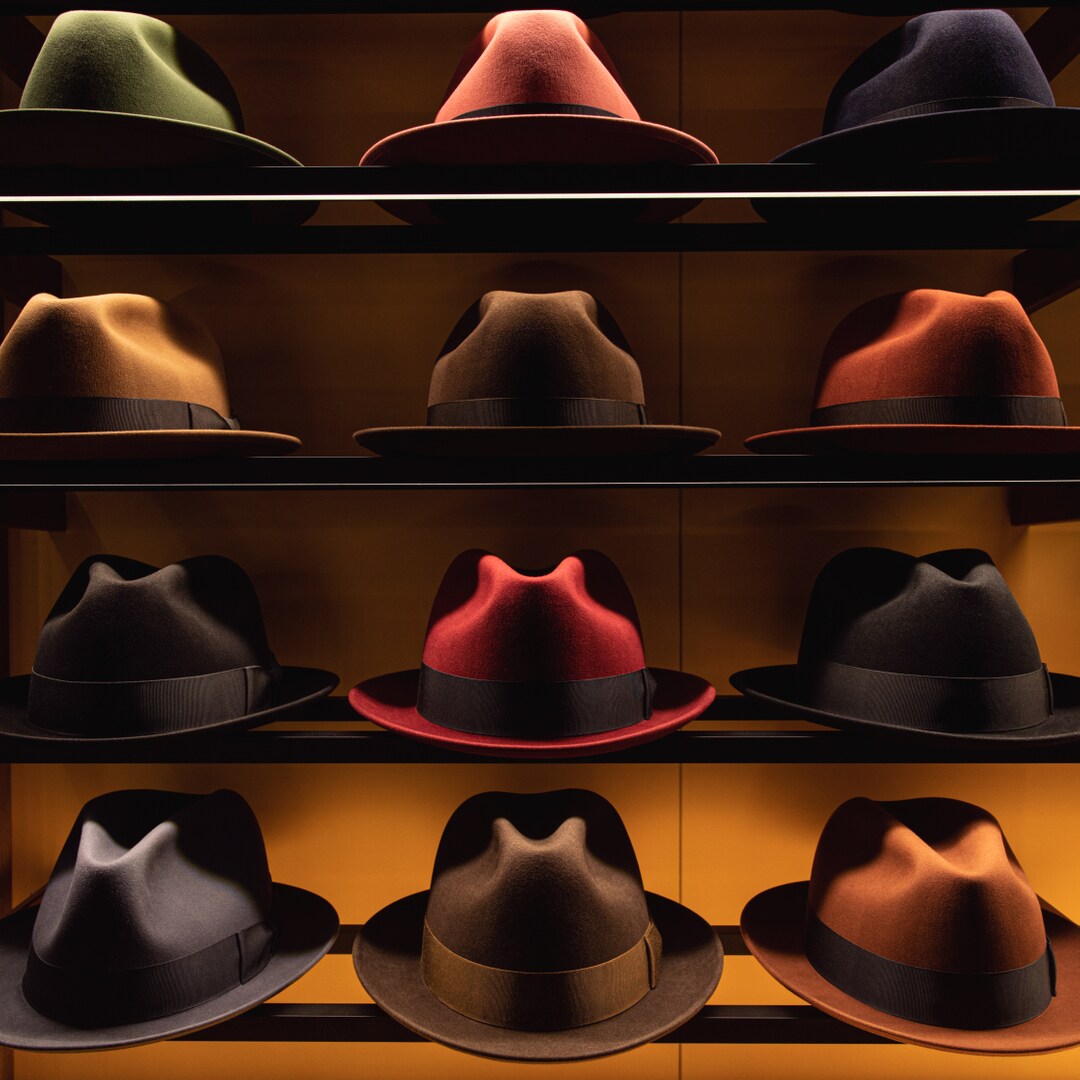 Artfully lit fedoras in a range of colors and brim styles line shelves at Optimo.