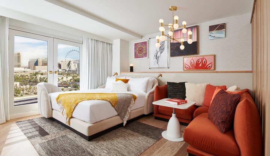 A Chamber King features a large bed in a bright room with an L-shaped couch, contemporary art on the walls, and doors opening onto a patio.